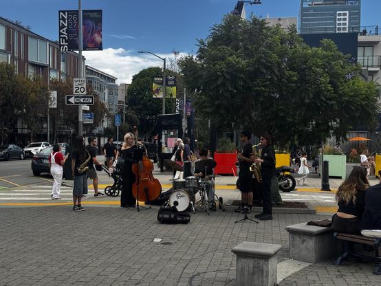 A group of youths playing bass, drum, and saxes in an open air plaza.